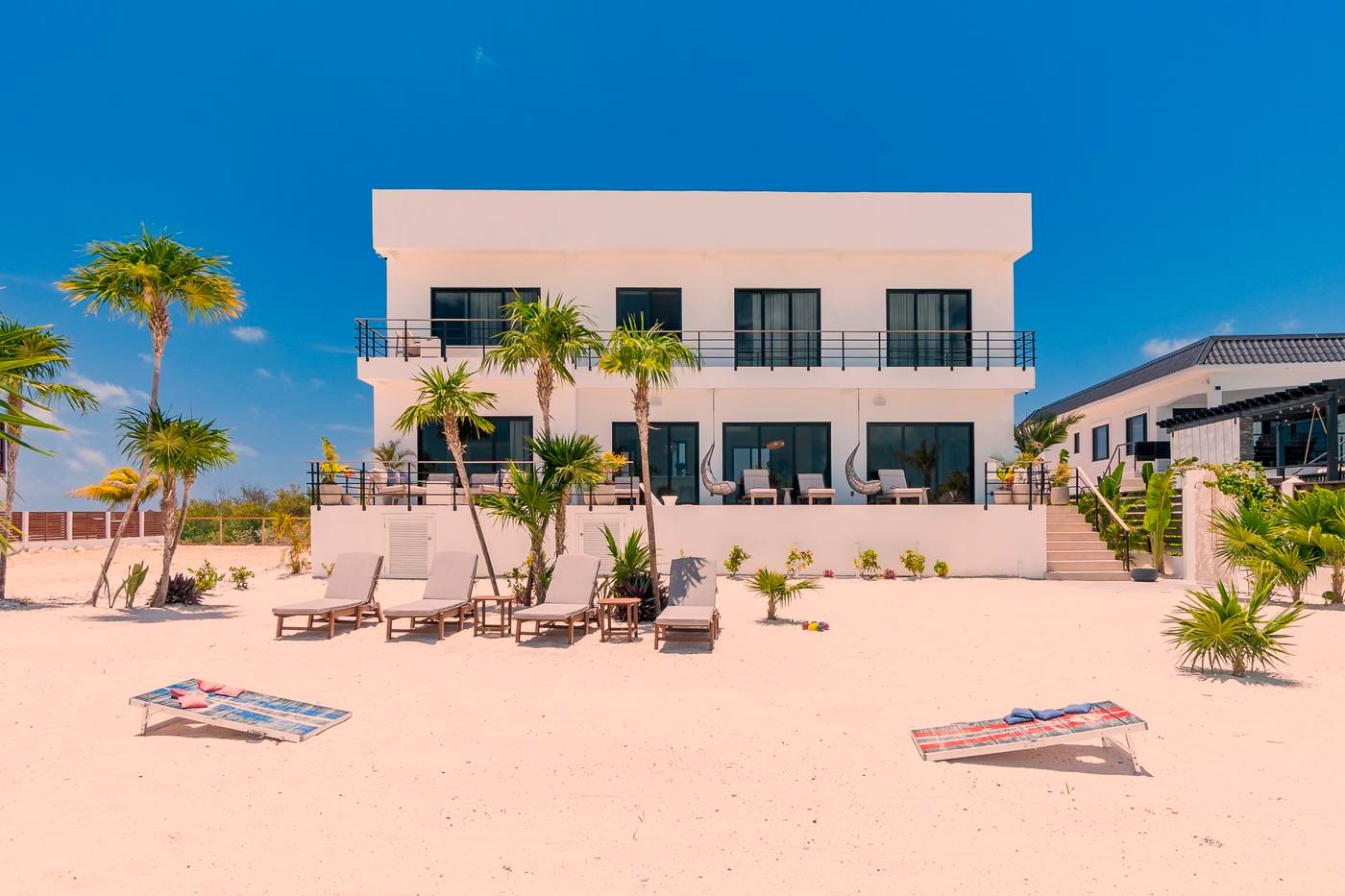 The villa seen from its beach, with cornhole boards set on the sand