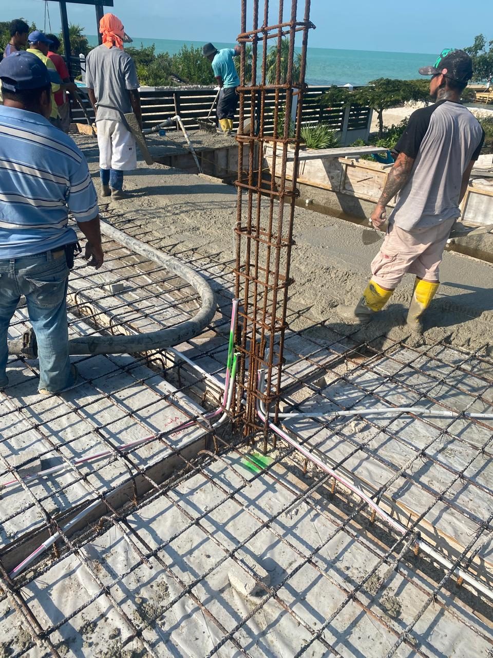 Local Belizean crew hand-pouring concrete on the rebar deck