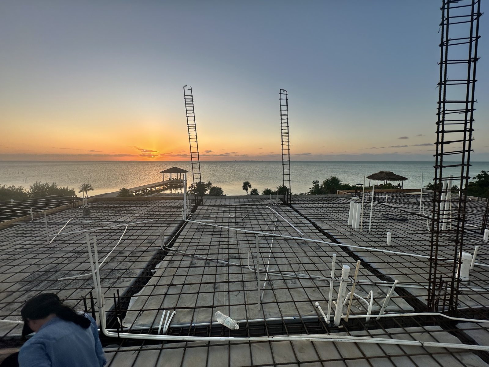 Rebar and conduit laid for a concrete slab pour at sunset, with the dock beyond